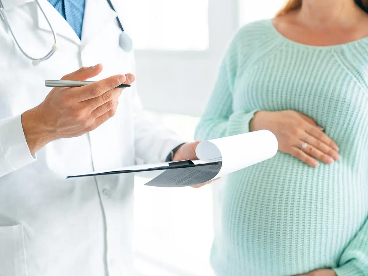 Médico hablando con una mujer embarazada sobre la rinoplastia y cuándo debería realizarse.