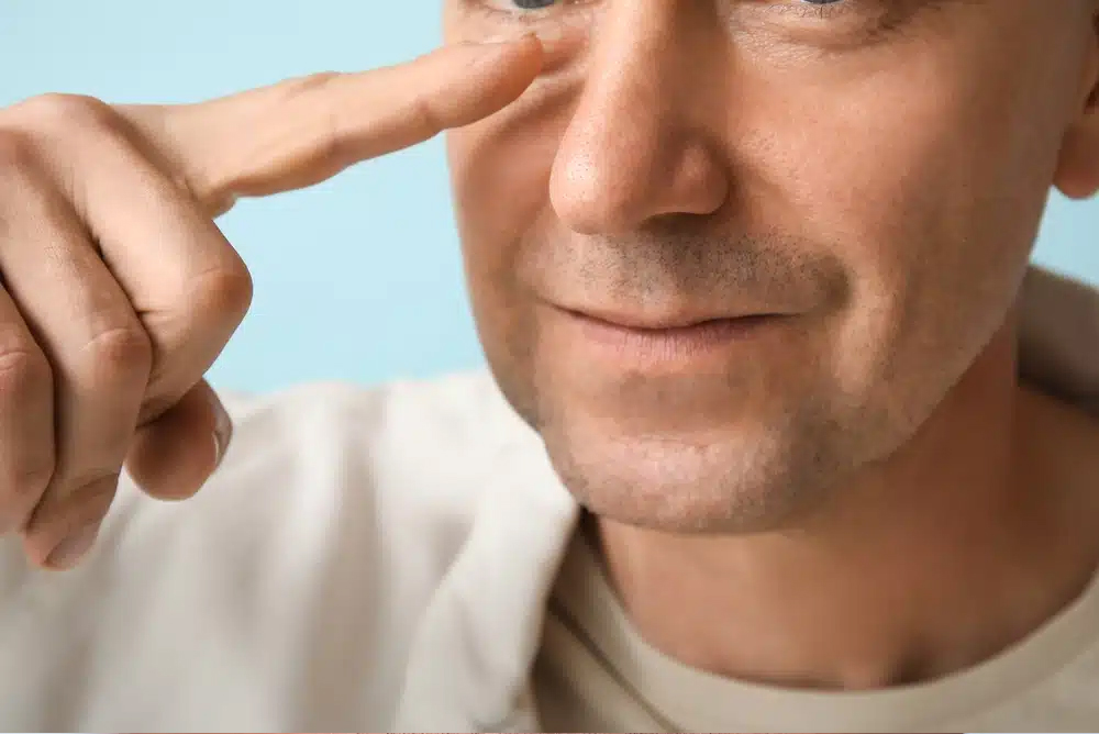 Primer plano de un hombre tocándose la nariz, representando la evaluación preoperatoria de la piel para rinoplastia.