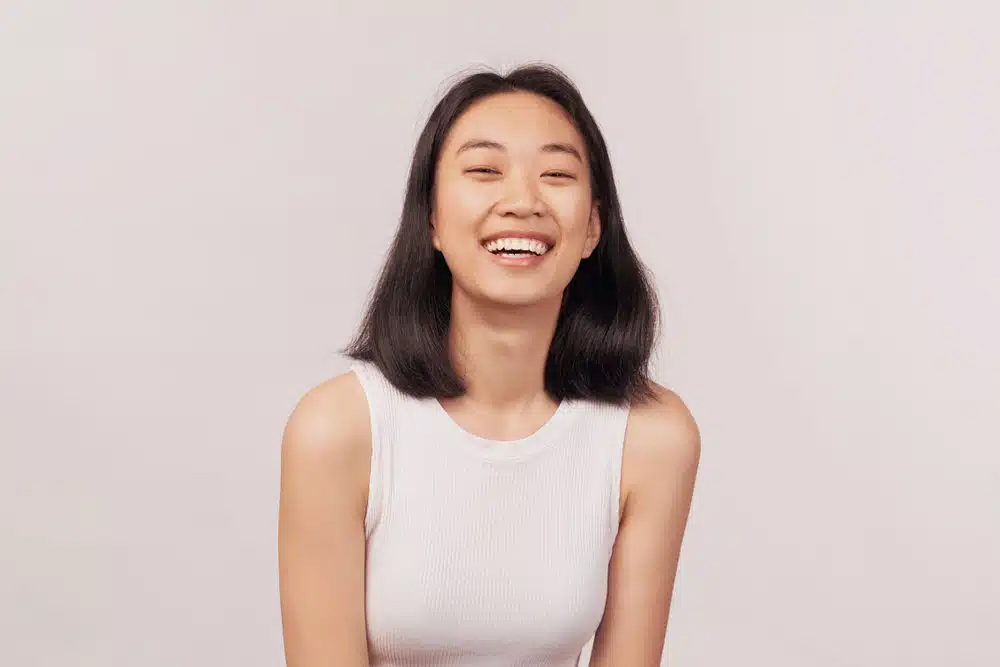 Mujer alegre con expresión natural, posible candidata para una rinoplastia personalizada.