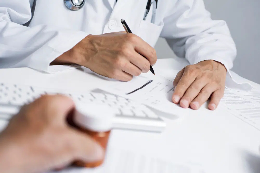 Médico revisando medicamentos con una paciente y explicando qué anticoagulantes debe evitar antes de la cirugía de lifting facial por seguridad.