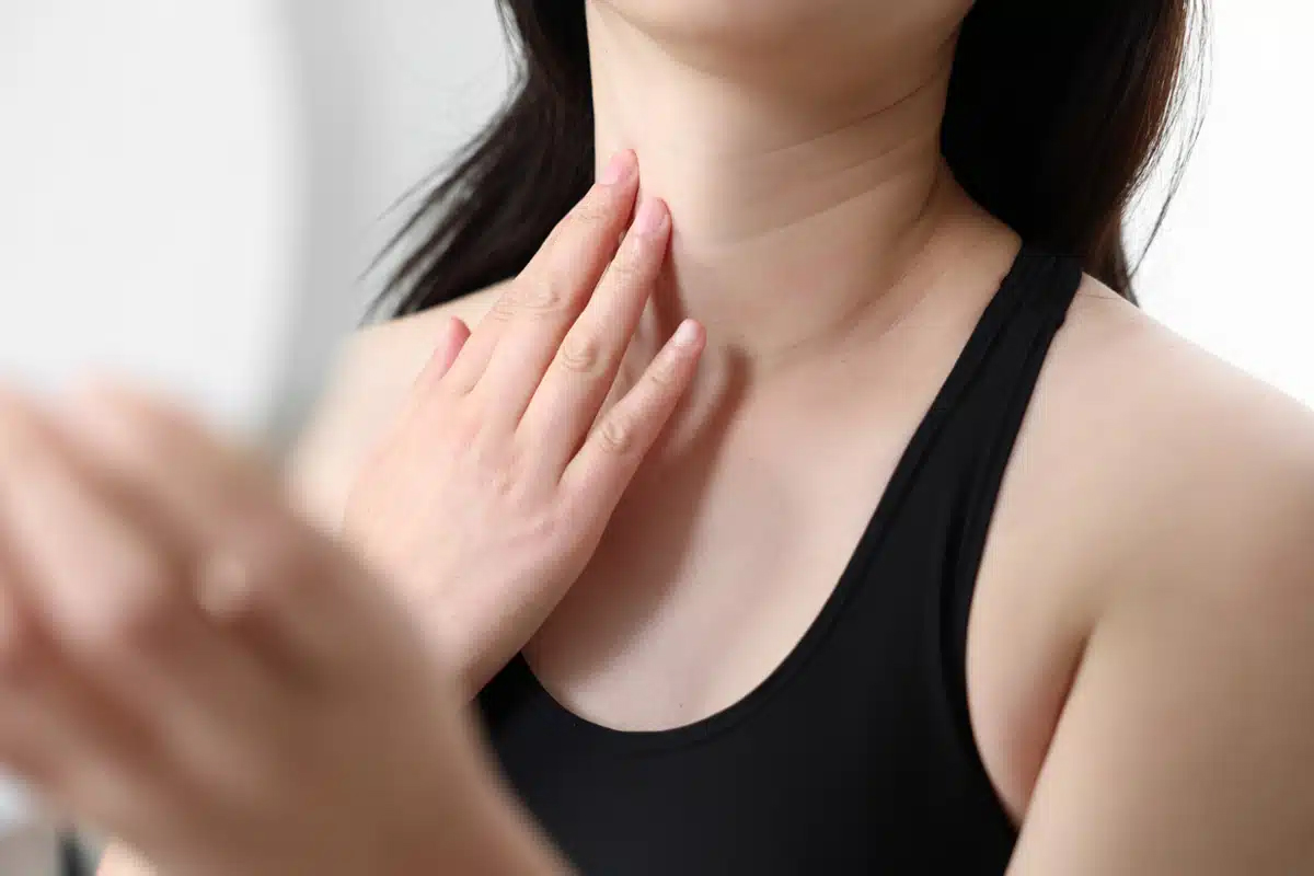Primer plano de una mujer tocando la piel firme de su cuello, representando los resultados de un lifting láser.