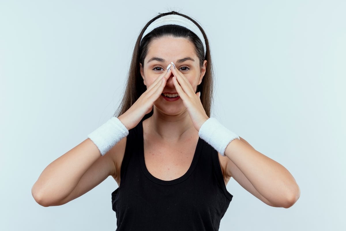 Mujer señalando su nariz, simbolizando el antes de una rinoplastia secundaria para alargar la nariz.
