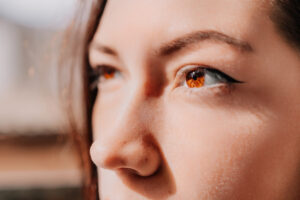 Primer plano del perfil nasal y los ojos de una mujer joven iluminados por la luz del sol.