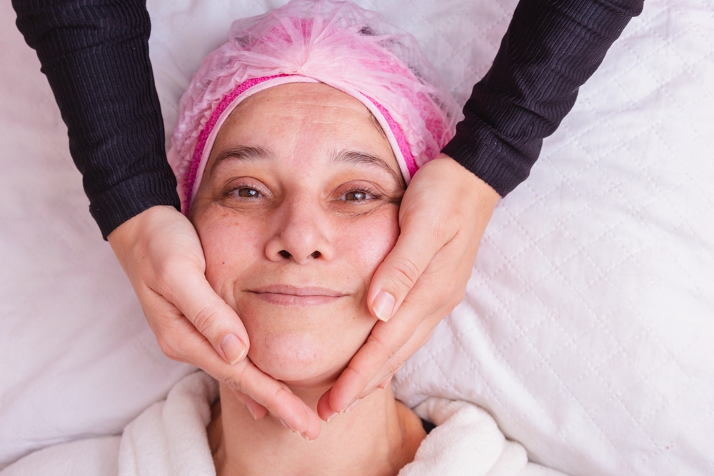 Mujer de mediana edad recibiendo una evaluación facial, destacando factores como la laxitud de la piel y el descenso de los tejidos para determinar el momento adecuado del lifting facial